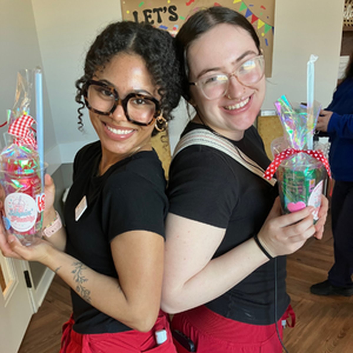 Two team members smiling with handmade gifts for residents