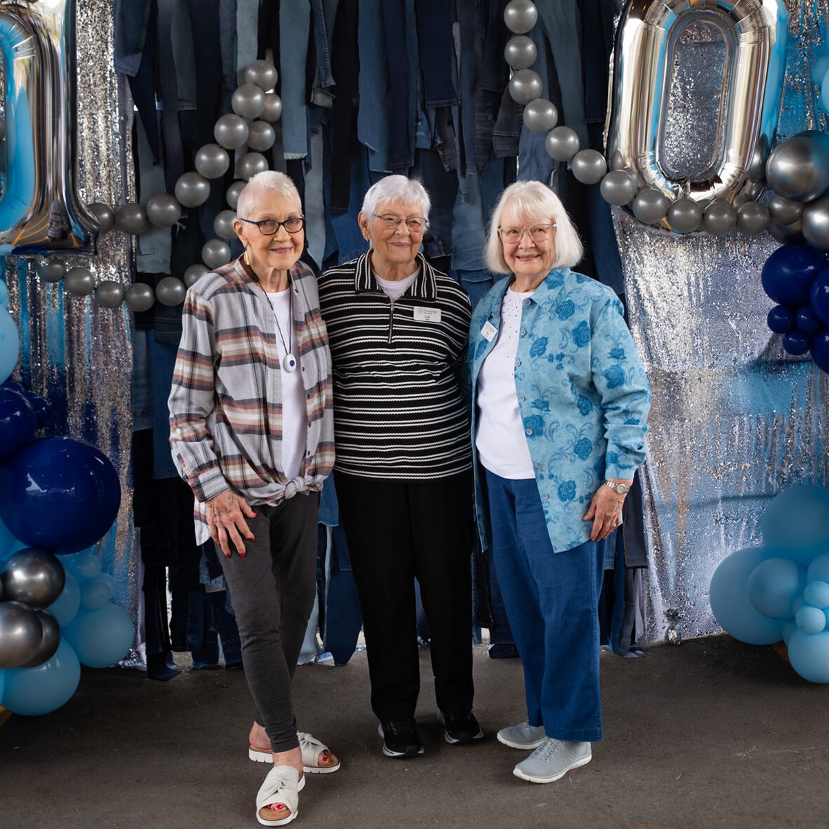Three friends posing together at a community anniversary party