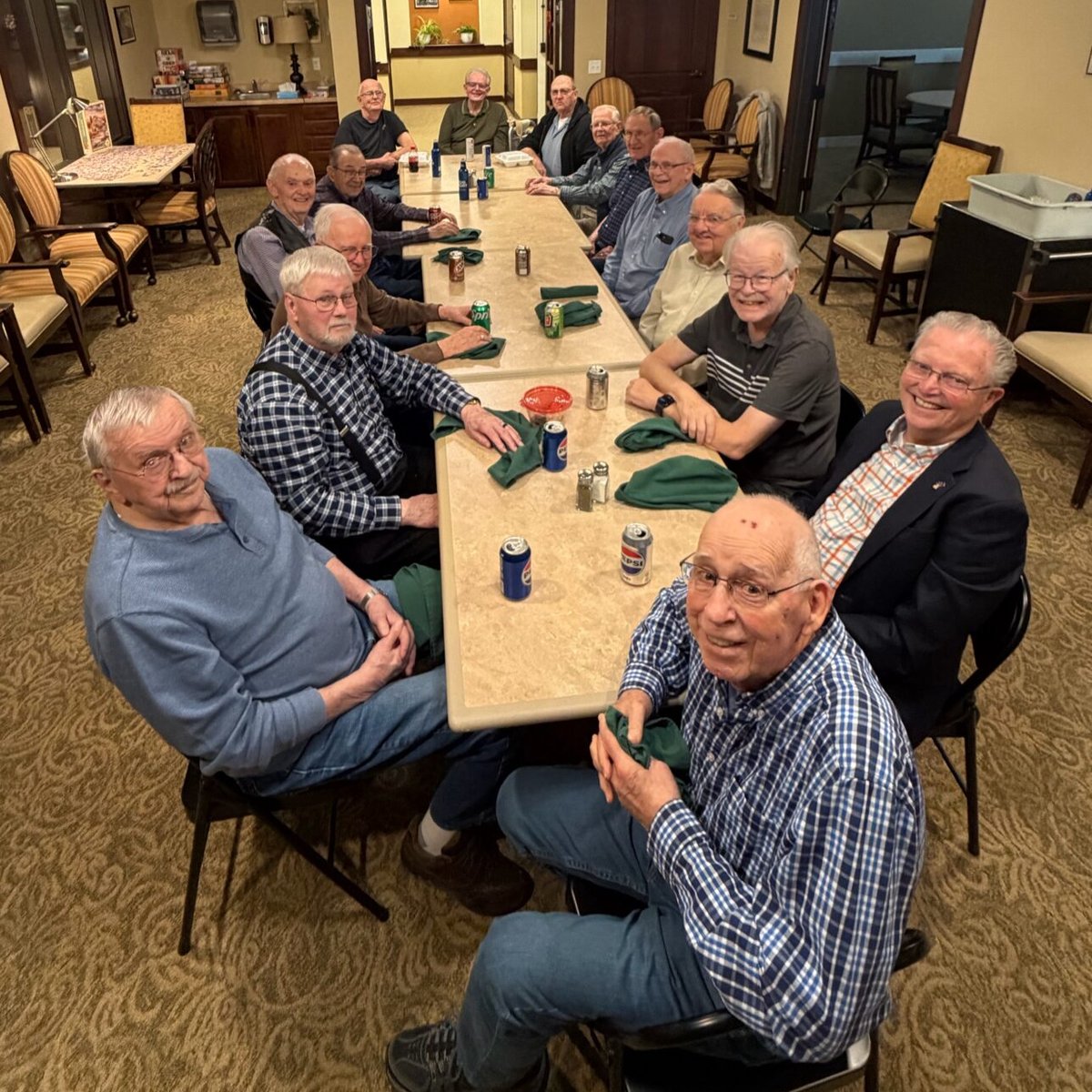 Residents gathered around a long table for a men's social hour